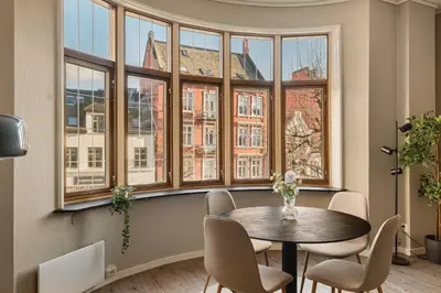 a table and chairs in a room with windows at Fløyen Suites - Private Rooms with the best location in Bergen in Bergen