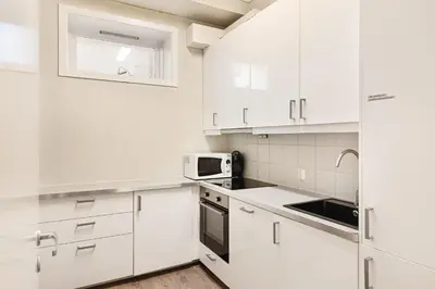a white kitchen with white cabinets and a microwave at Fløyen Suites - Private Rooms with the best location in Bergen in Bergen
