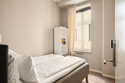 a white bedroom with a bed and a window at Fløyen Suites - Private Rooms with the best location in Bergen in Bergen