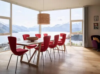 a dining room with a table and red chairs at Villa Fjord View in Stranda