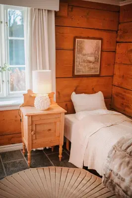 a bedroom with a bed and a table with a lamp at Helgaker Gård in Gran