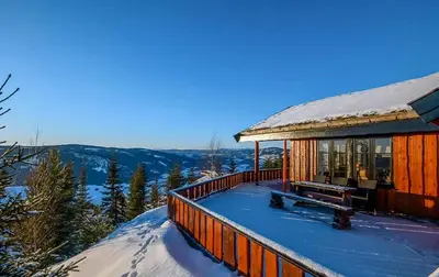 a cabin in the snow with a bench on the deck at Modern Cabin With Ski In-Out In Hafjell in Øyer
