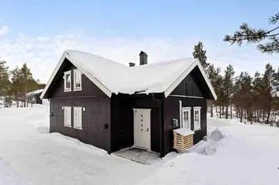 a black house with a snow covered roof in the snow at Ny, stor hytte nær Røros sentrum! in Røros