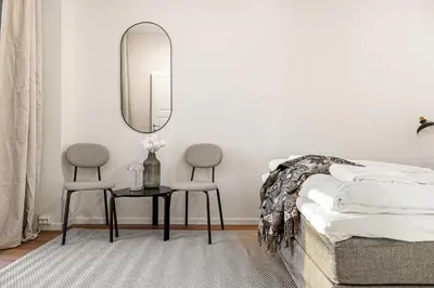 a bedroom with a bed and two chairs and a mirror at Heimby Homes - Balcony above the sea in Bergen