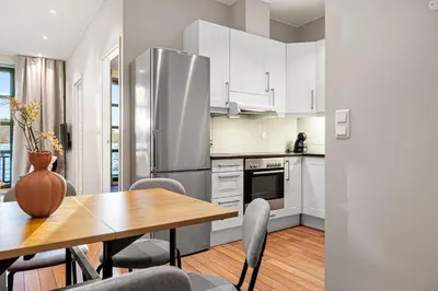a kitchen with a table and a stainless steel refrigerator at Heimby Homes - Balcony above the sea in Bergen