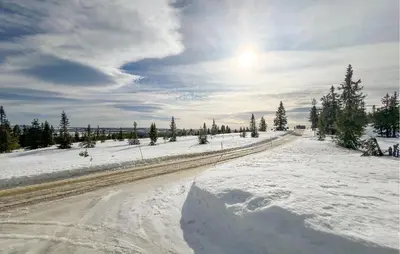 a road covered in snow with the sun in the sky at Beautiful Home In Vang På Hedmarken in Sæli
