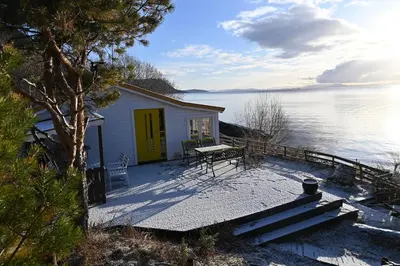 a small house with a table and a bench on a dock at En perle i Trondheimsfjorden in Trondheim