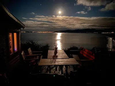 a dock on a lake at night with a full moon at En perle i Trondheimsfjorden in Trondheim