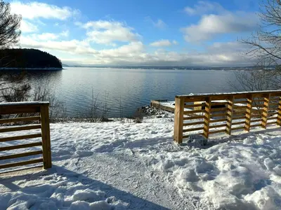 a wooden fence in the snow next to a body of water at Cabin By Lake Tyrifjorden With Water Views