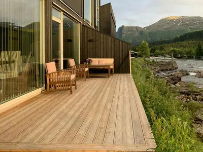 a wooden deck with a table and chairs on a house at Cabin By Heimsila River In Hemsedal in Hemsedal
