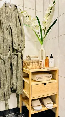 a bathroom with a shelf with towels and a vase of flowers at Modern Suites, Excellent Location in the heart of Bergen in Bergen