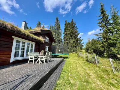a wooden deck with a table and a house at Traditional mountain cabin in Valdres in Blomstølen