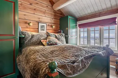a bedroom with a bed in a room with wooden walls at Tømmerhytte i Valdres med panoramautsikt over fjellene in Aurdal