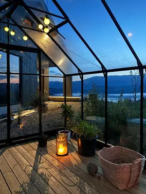 a glass greenhouse with a candle on a wooden deck at Cabin Overlooking Ryfylke Fjord in Høyvik