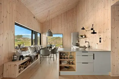 a kitchen and dining room with a table and chairs at Cabin Overlooking Ryfylke Fjord in Høyvik
