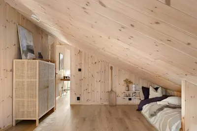 an attic bedroom with wooden walls and a bed at Cabin Overlooking Ryfylke Fjord in Høyvik