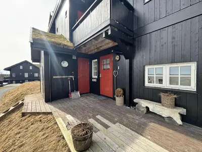 a house with a red door and a wooden deck at Fully equipped ski-in ski-out apartment at Kikut, Geilo in Geilo