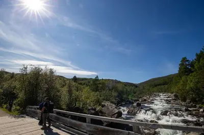 a man walking on a bridge over a river at Fully equipped ski-in ski-out apartment at Kikut, Geilo in Geilo