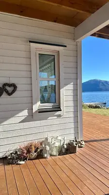 a porch of a house with a window and flowers at Live right by the Sognefjord in Sogndal