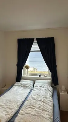 a bedroom with a window with a view of the beach at Live right by the Sognefjord in Sogndal