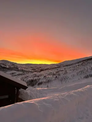 a sunset over a snow covered field with a ski slope at Modern Cabin With A Personal Touch in Sogndal