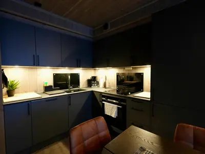 a kitchen with blue cabinets and a table with chairs at Ski in & out - Hemsedal in Kyrkjebøen