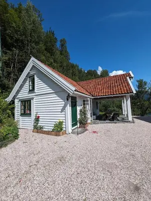 a small white house with a red roof at Charming guest house with amazing view in Kvam