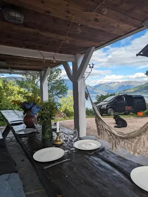 a table with chairs and a hammock with a view of a car at Charming guest house with amazing view in Kvam