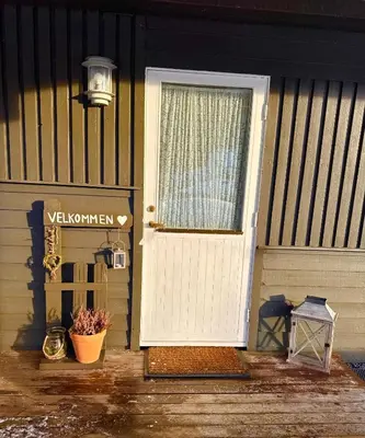 a white door with a sign on a house at Kjellerleilighet in Bjørge