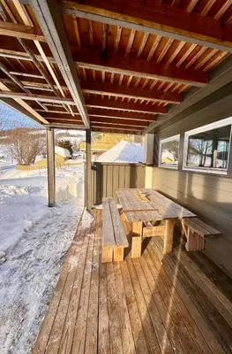 a wooden picnic table on a wooden deck with snow at Kjellerleilighet in Bjørge