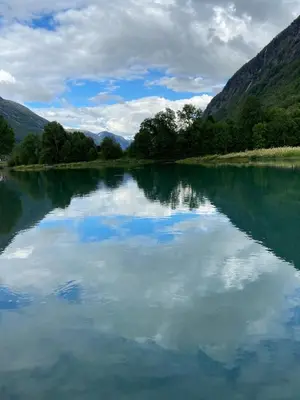 a lake with a reflection of the sky in the water at Faleide View in Stryn