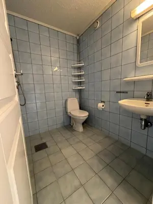 a blue tiled bathroom with a toilet and a sink at Faleide View in Stryn