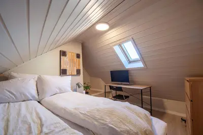 a bedroom with a bed and a desk with a computer at 200 meters to Bryggen in charming Sandviken in Bergen