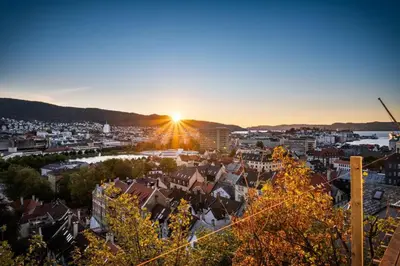 a city with the sun setting in the background at Stay Panorama - Best view in Bergen l Studio in Bergen