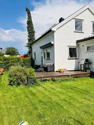 a white house with a wooden deck in the yard at Beautiful spacious home w garden in Trondheim