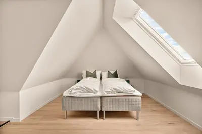 a bed with white sheets and pillows in a attic at Stay Panorama - Best view in Bergen l 2-Bedroom in Bergen