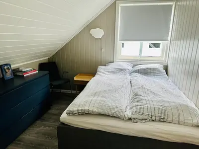 a bedroom with a bed with a window and a desk at Scenic Private House Surrounded by Nature in Sæbø