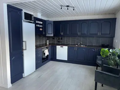 a kitchen with blue cabinets and a white refrigerator at Scenic Private House Surrounded by Nature in Sæbø