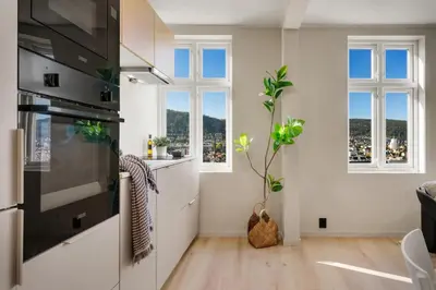 a kitchen with white cabinets and two windows at Stay Panorama - Best view in Bergen l 2BR & Terrace in Bergen