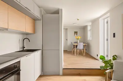 a kitchen with white cabinets and a table with chairs at Stay Panorama - Best view in Bergen l 2BR & Terrace in Bergen