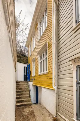 a yellow building with stairs next to a house at Stay Panorama - Best view in Bergen l 2BR & Terrace in Bergen