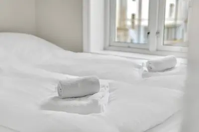 two towels sitting on top of a white bed at Urban Elegant Apartment in Bergen