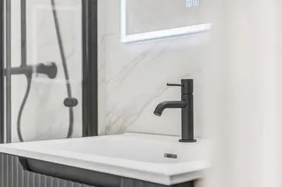 a bathroom with a white sink and a shower at Urban Elegant Apartment in Bergen