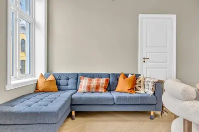 a blue couch with orange pillows in a living room at Urban Elegant Apartment in Bergen