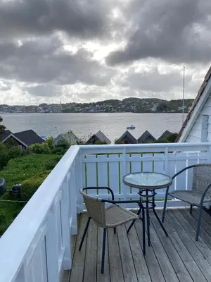 a table and chairs on a deck with a view of the water at Short way to city centre and Aker Solutions! in Stord