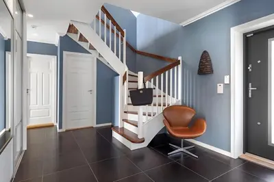 a hallway with blue walls and a staircase with a chair at Beachfront Villa with Jacuzzi, Cinema & Canoe in Bergen