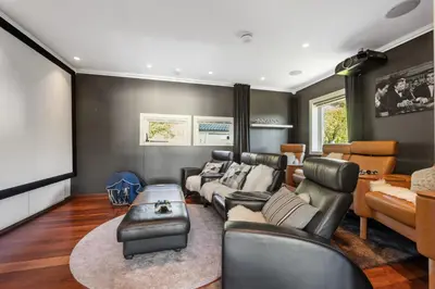 a living room with leather furniture and a flat screen tv at Beachfront Villa with Jacuzzi, Cinema & Canoe in Bergen
