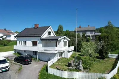 a white house with a car parked in front of it at Leilighet i under etasje in Lillehammer