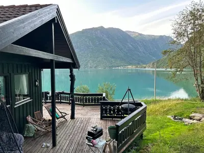 a house with a deck with a view of a lake at Cabin by Oppstrynsvatnet, Hjelle in Stryn