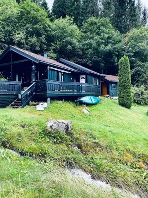a house on a field with a boat in front of it at Cabin by Oppstrynsvatnet, Hjelle in Stryn